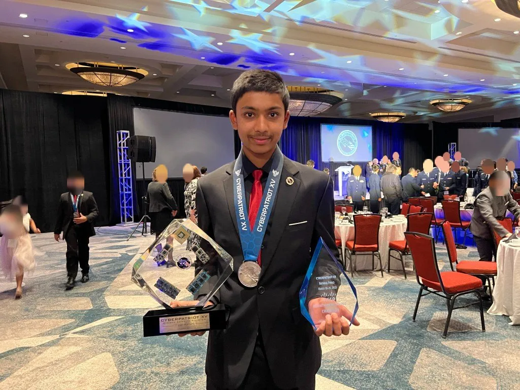 Aditya holding the CyberPatriot XV national finals trophy and medal