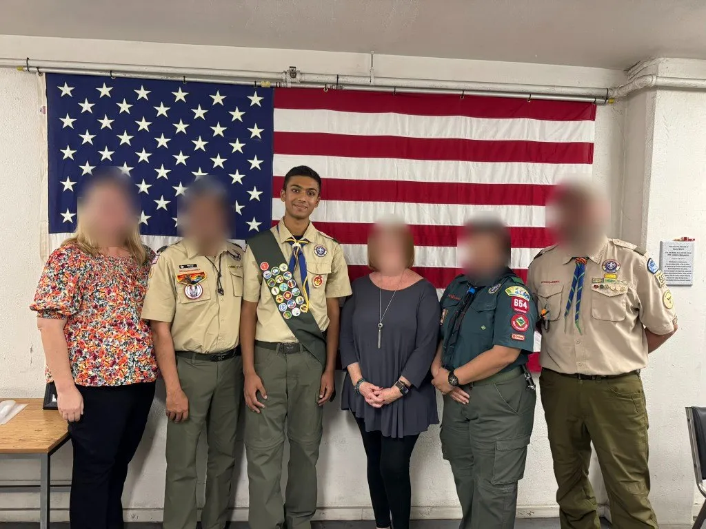Aditya at his Eagle Scout ceremony with scout leaders; other faces blurred