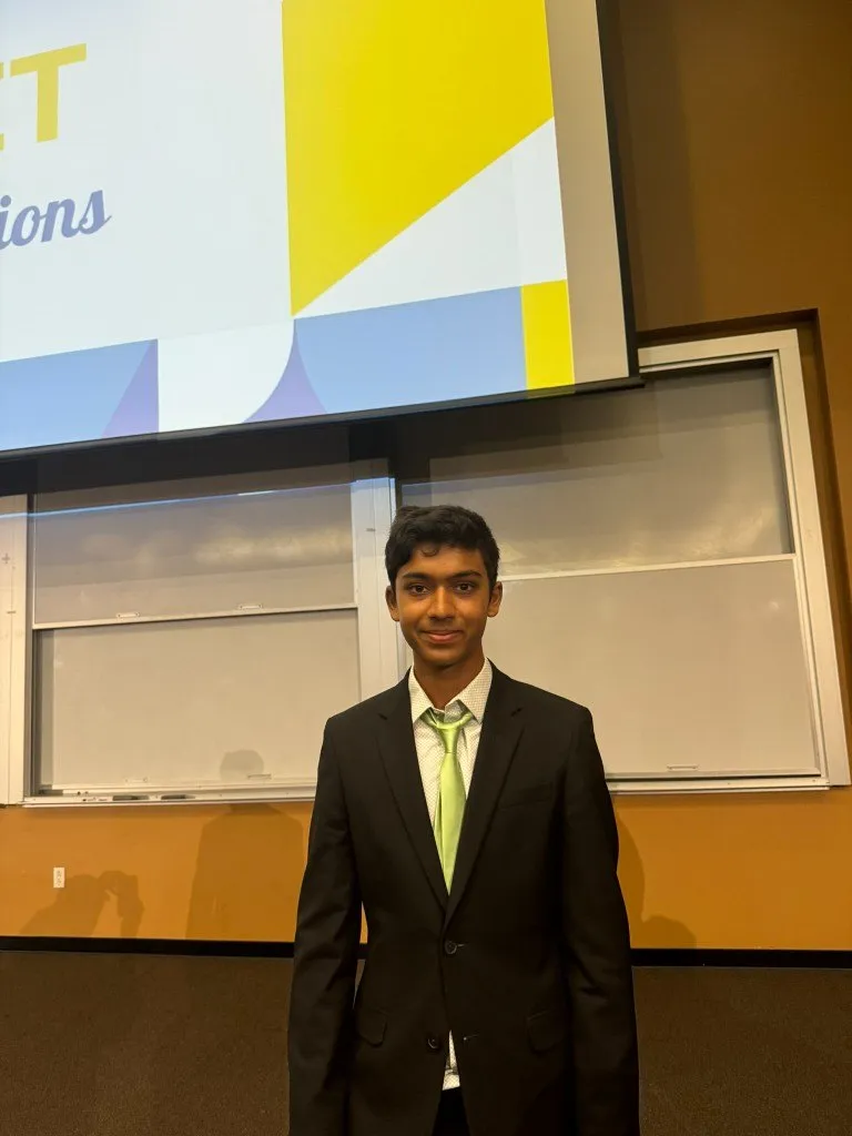 Aditya in a suit in front of the presentation screen at UC Irvine