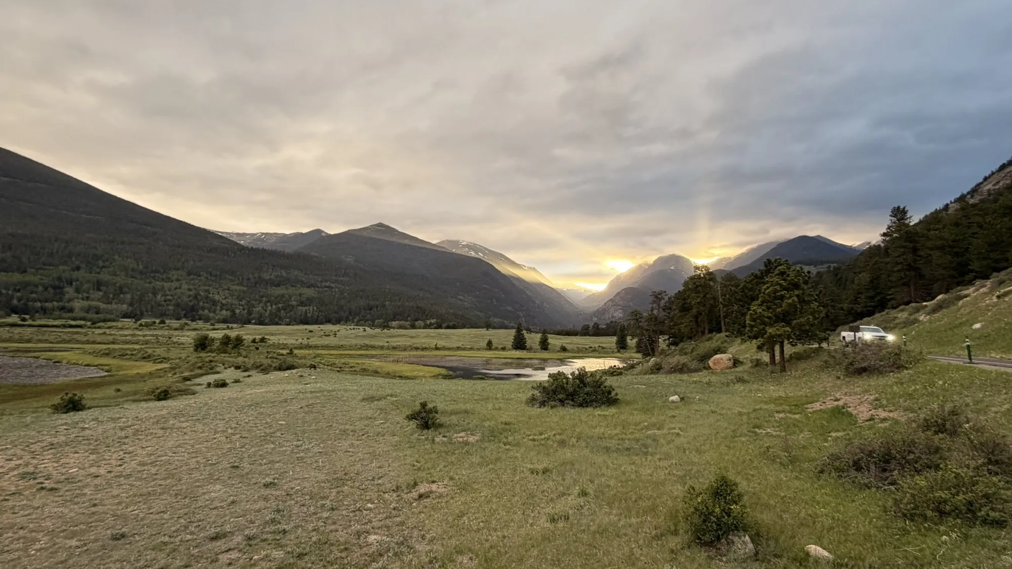 Sun setting over a mountain meadow and a small pond