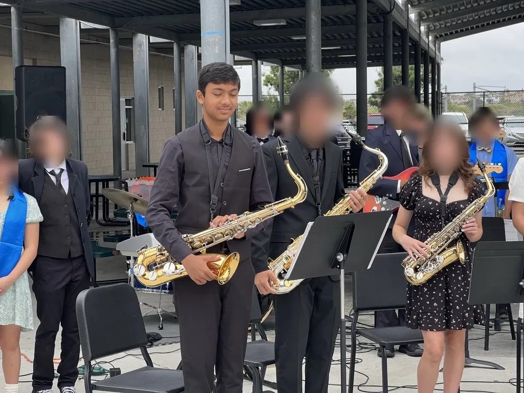 Aditya standing with the saxophone section after a concert; other faces blurred