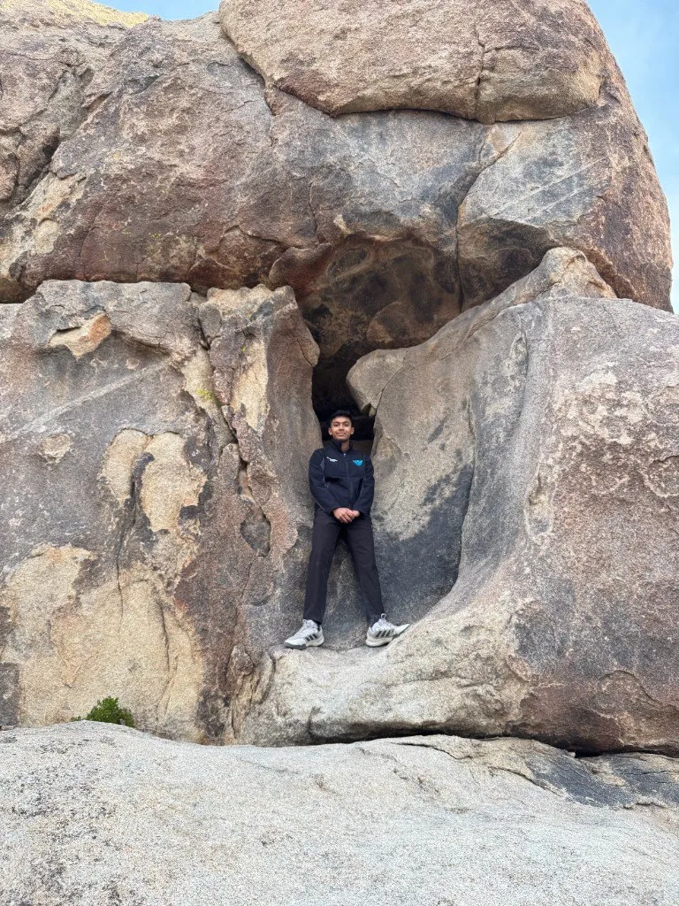 Aditya standing in a gap between huge granite boulders